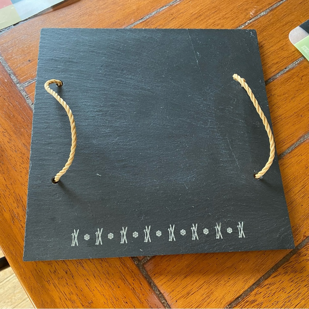 Slate cheese plate engraved with skis and delicate snowflakes. Two ropes handle